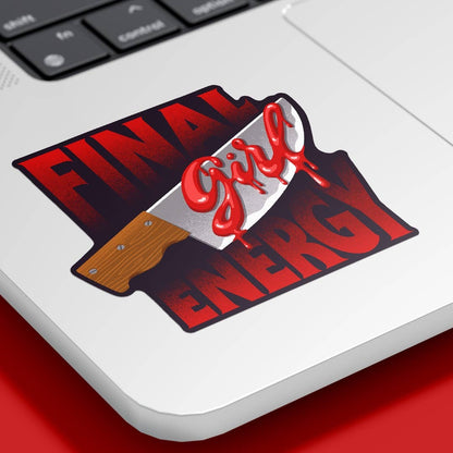 A die-cut sticker featuring the text 'FINAL Girl ENERGY' in red and black, with a bloody knife graphic, shown applied to the corner of a silver laptop on a red surface.
