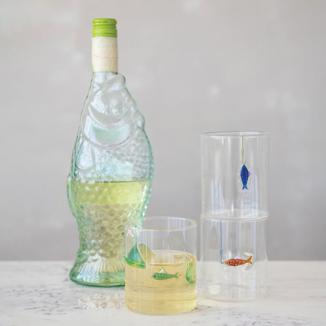Bottle and glasses with fish illustrations on a light gray background