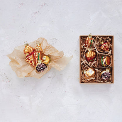  food themed Christmas ornaments in a box on a textured white surface