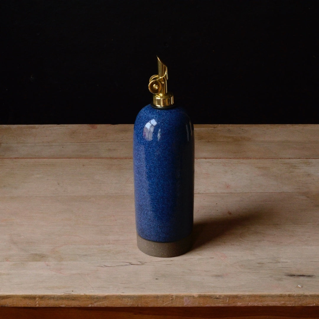 Blue ceramic oil cruet with gold cap on a wooden surface