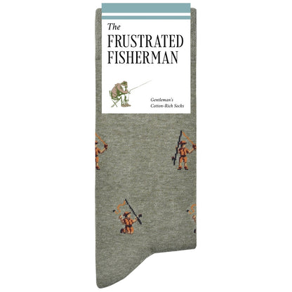 A single sock with a heather gray base and a repeating pattern of orange and brown fisherman figures, featuring a white paper label at the top with the text 'The Frustrated Fisherman' and 'Gentleman's Cotton-Rich Socks'.