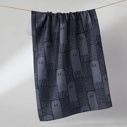 A dark gray kitchen towel with a repeating ghost pattern, hanging from a thin rope against a light gray background.