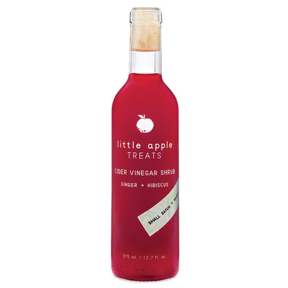 Red bottle of 'little apple treats' hibiscus ginger cider vinegar shrub with a white label on a white background