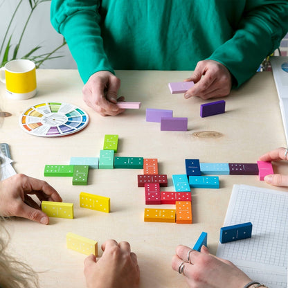 People playing with colorful wooden dominoes on a table