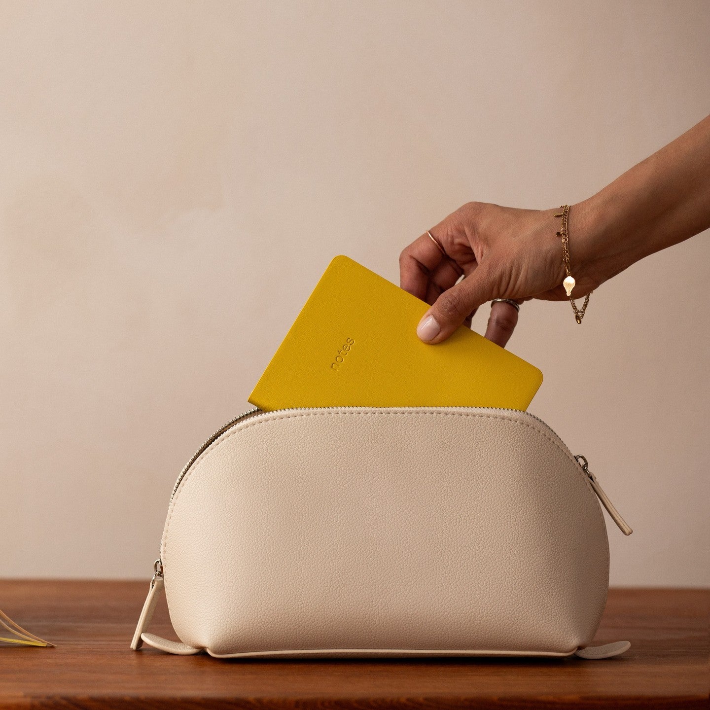 Hand pulling out small yellow notebook out of clutch bag.