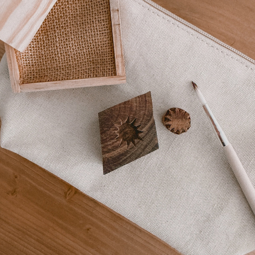 close up of a pine ink tray, paintbrush, and 2 wooden block stamps on a canvas pouch