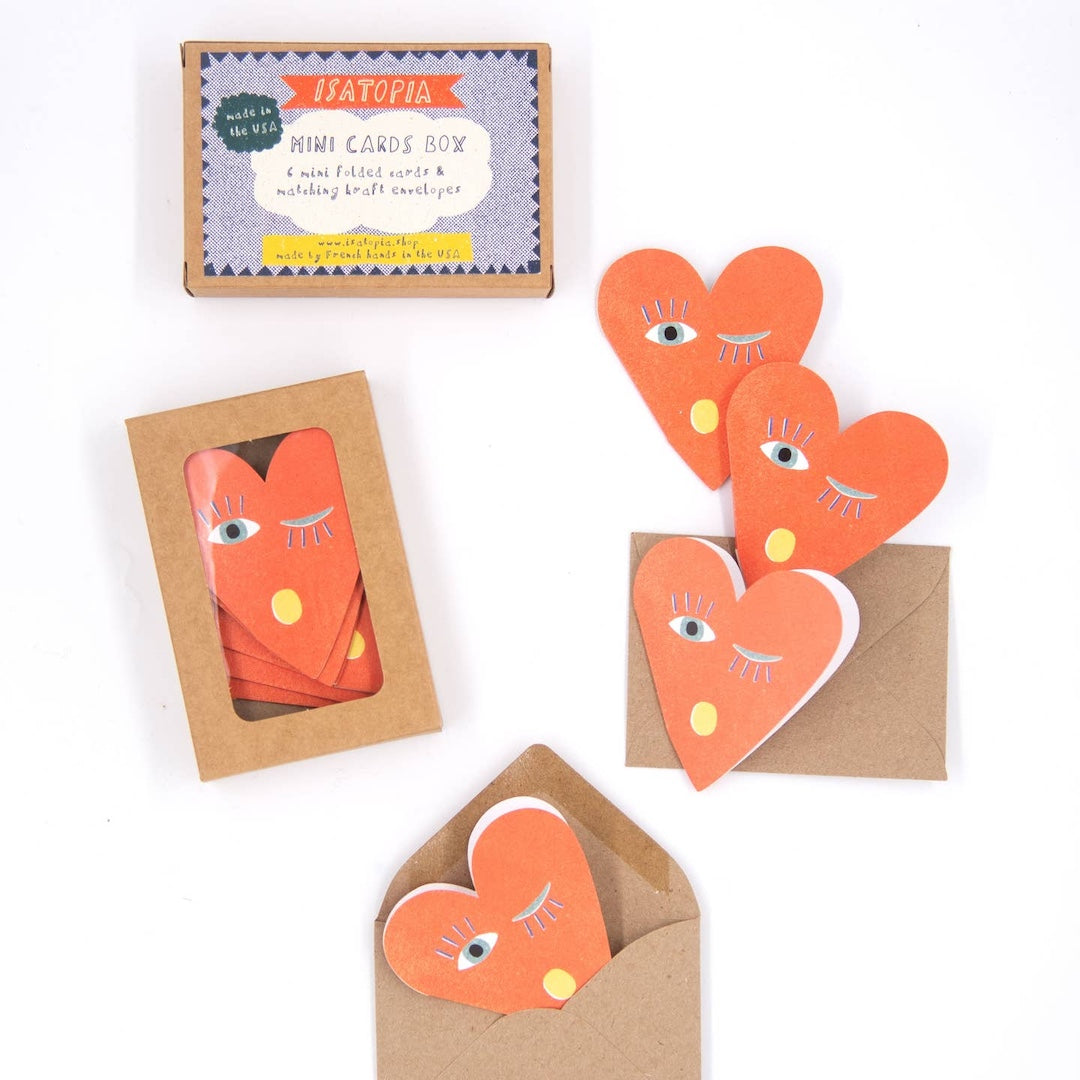 Heart-shaped cards with facial expressions on a white background, featuring a mini card box.