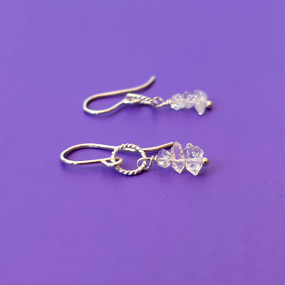 Silver earrings with herkimer diamonds on a purple background