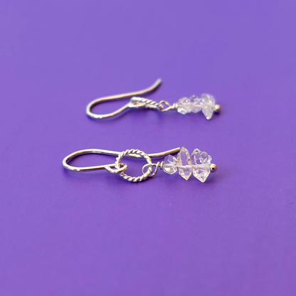 Silver earrings with herkimer diamonds on a purple background
