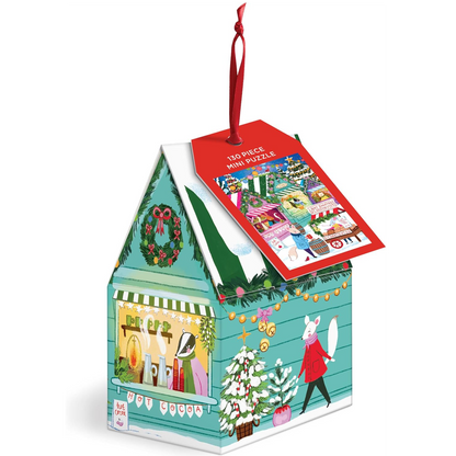 A 130-piece Christmas mini puzzle in the shape of a house-shaped box with a red hanging ribbon and a red product tag. The box is decorated with festive illustrations including a wreath, string lights, a Christmas tree, and a rabbit in a red coat on a white background.
