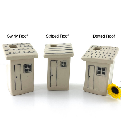 Three small house-shaped ceramic items labeled 'Swirly Roof,' 'Striped Roof,' and 'Dotted Roof' on a white background, with a small yellow flower at the bottom right.