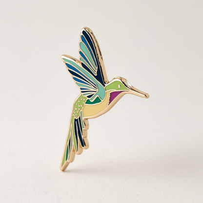 Colorful hummingbird-shaped pin on a light gray background