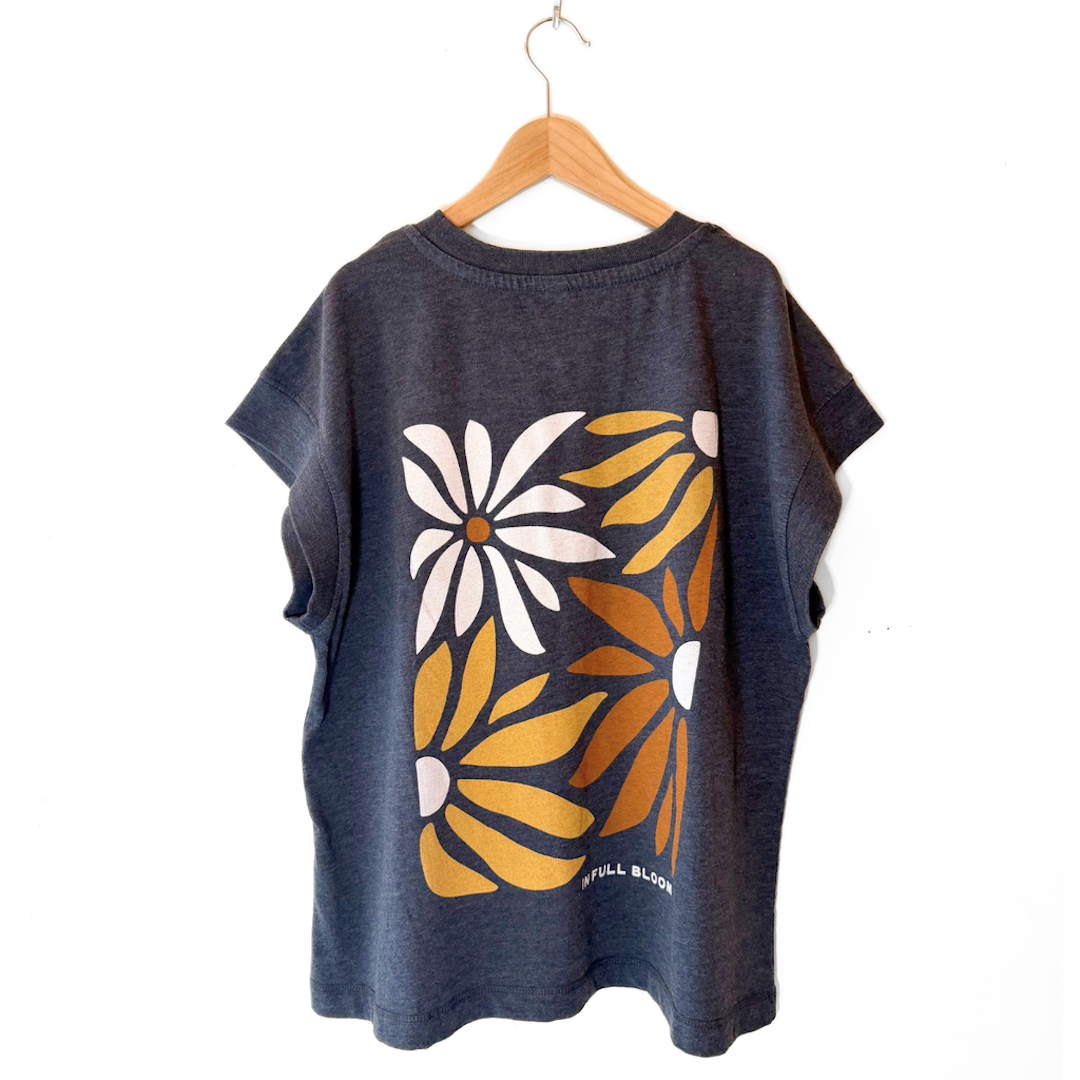 Dark blue t-shirt with yellow and white floral design on a wooden hanger against a white background