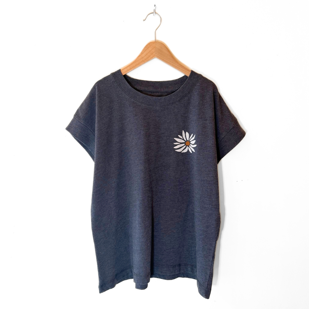 Blue t-shirt with a white flower design on a wooden hanger against a white background