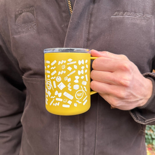 A person wearing a brown jacket holds a yellow enamel mug with a clear lid. The mug is decorated with white doodle-style icons and features the brand name 'Bimse' on the handle and on the jacket.