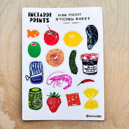 A white sticker sheet from Inciardi Prints featuring colorful illustrated mini stickers of food items like a tomato, lemon, mussels, bagel, cucumber, shrimp, jam, and pasta, displayed flat on a light wood background.