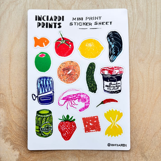 A white sticker sheet from Inciardi Prints featuring colorful illustrated mini stickers of food items like a tomato, lemon, mussels, bagel, cucumber, shrimp, jam, and pasta, displayed flat on a light wood background.