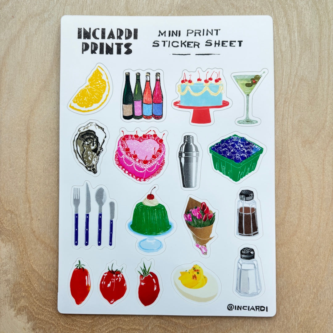 A white sticker sheet from Incardi Prints featuring various colorful mini illustrations, including drinks, desserts, tableware, and food, laid flat on a light wood surface.