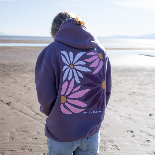 Person wearing a purple hoodie with floral designs on the back at the beach