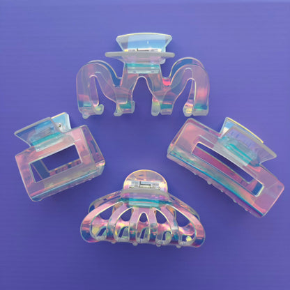 Set of four iridescent hair clips on a purple background