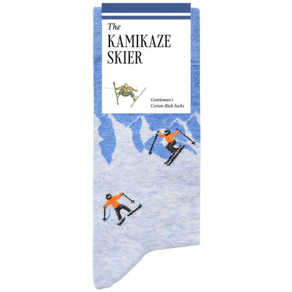 A pair of knit socks with a light blue and white mountain pattern and skiers printed on them, featuring a white paper header card that reads 'The KAMIKAZE SKIER'.