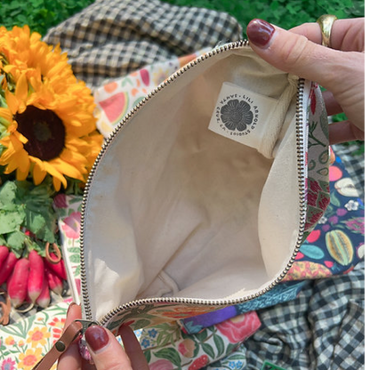 Colorful floral-patterned bag with a brand label, held open by hands against a natural background.