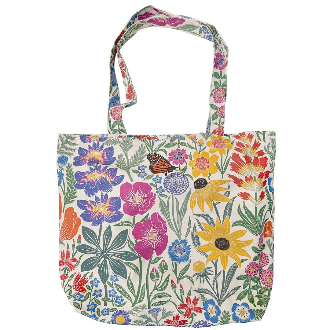 A canvas tote bag featuring a vibrant, multicolor wildflower and butterfly pattern on a cream background, shown against a plain white studio background.