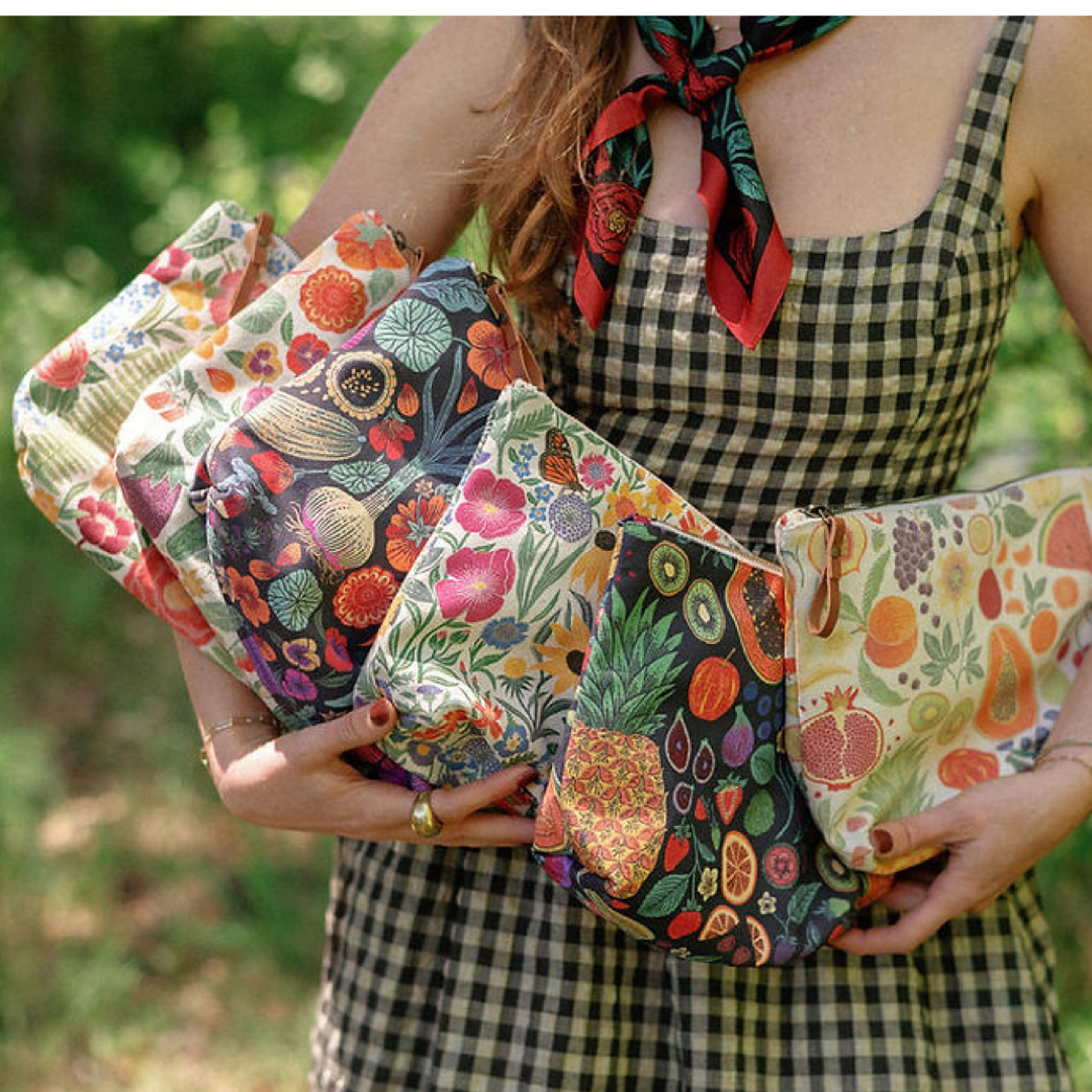 Person holding colorful patterned pouches with a blurred green background