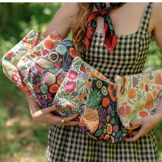 Person holding colorful patterned pouches with a blurred green background