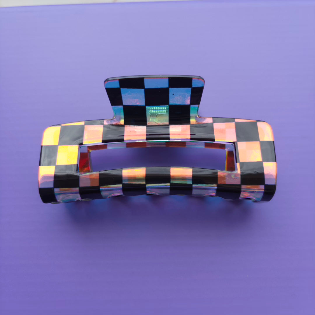Iridescent and black checkered hair clip on a purple background