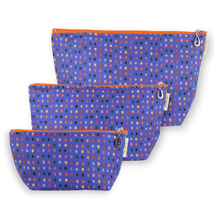 Three fabric zip pouches in a nested set, featuring a purple background with a multicolor dotted pattern and bright orange zippers.