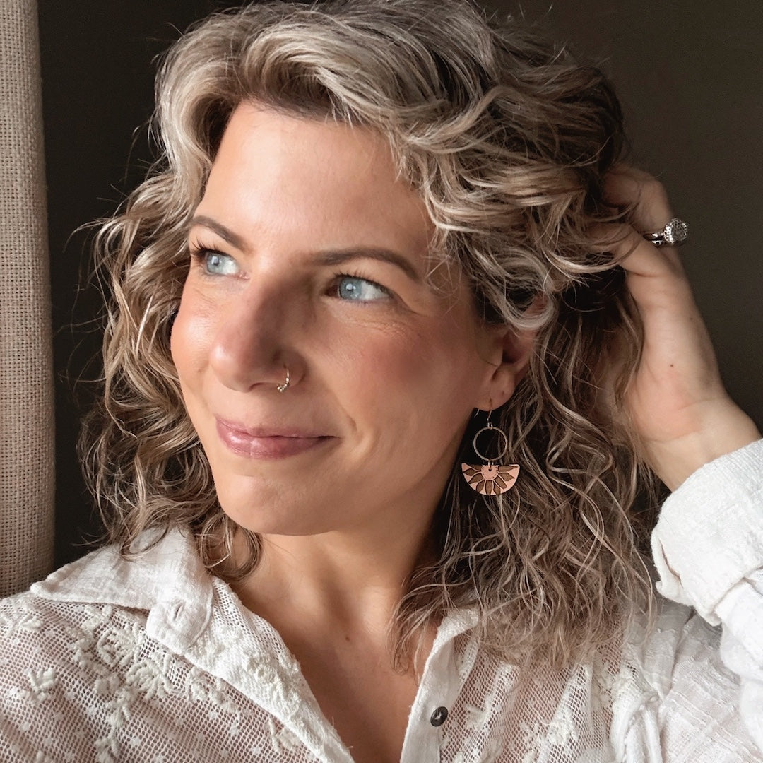 Woman with blonde hair and blue eyes wearing a white lace shirt.