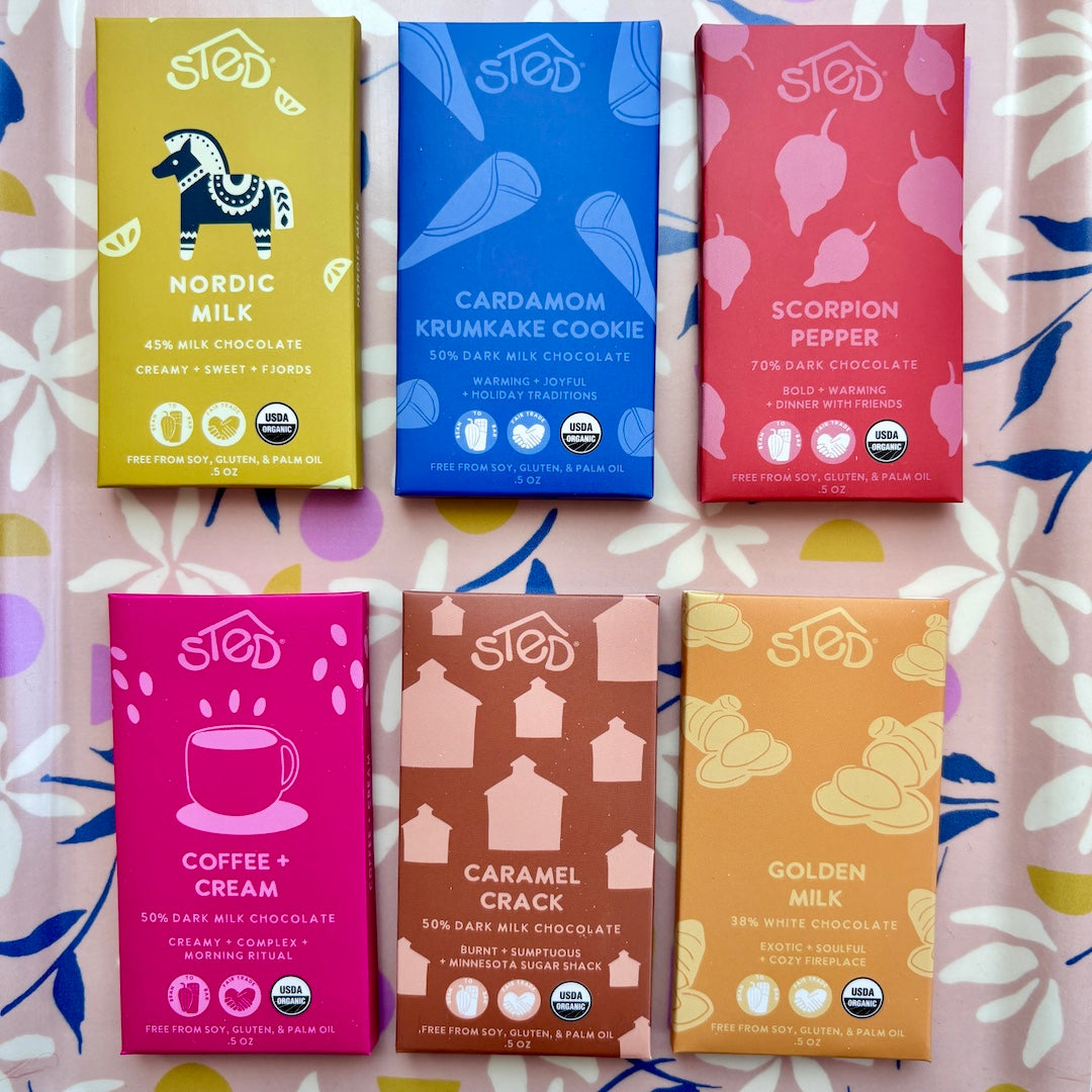 Six different chocolate bars with colorful packaging on a patterned surface