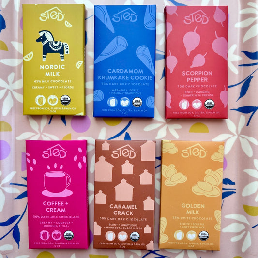 Six different chocolate bars with colorful packaging on a patterned surface