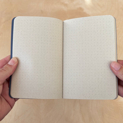 Open notebook with dotted pages held by a person on a wooden surface