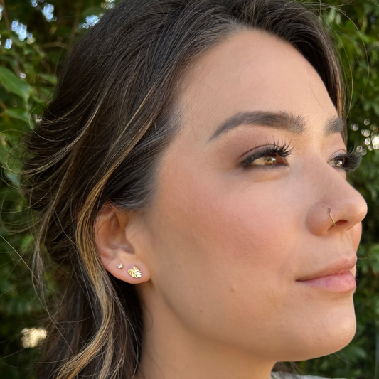 Close-up of a woman's face with earrings against a green outdoor background