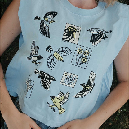 Light blue t-shirt with bird illustrations worn by a person outdoors