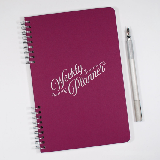 Purple weekly planner with a pen on a white background