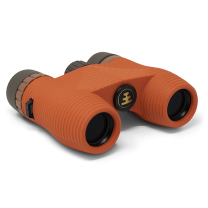 Orange binoculars with a textured rubberized grip and a black central logo badge, shown on a clean white background.