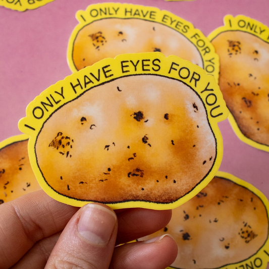 Sticker of a potato with text 'I only have eyes for you' held by a hand on a pink background.