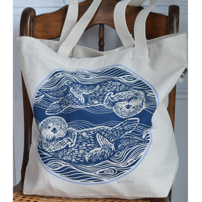 canvas tote bag with two otters in the water printed in blue on the tote