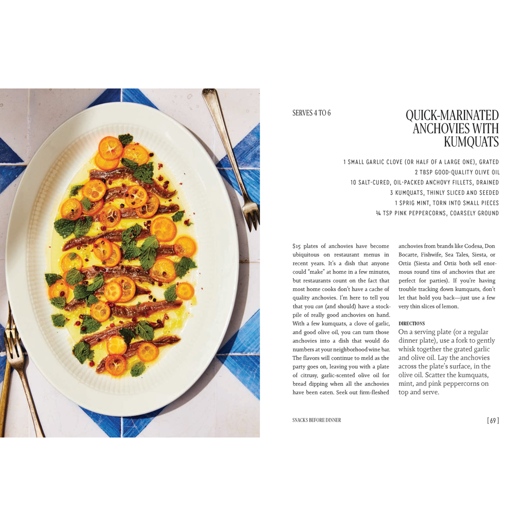 A cookbook page showing a plated dish of anchovies on runciforms with orange slices, alongside recipe text and ingredients. The plate is photographed on a white page with black text and silver utensils visible.