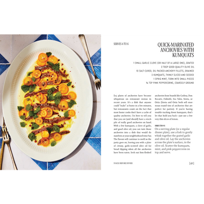 A cookbook page showing a plated dish of anchovies on runciforms with orange slices, alongside recipe text and ingredients. The plate is photographed on a white page with black text and silver utensils visible.