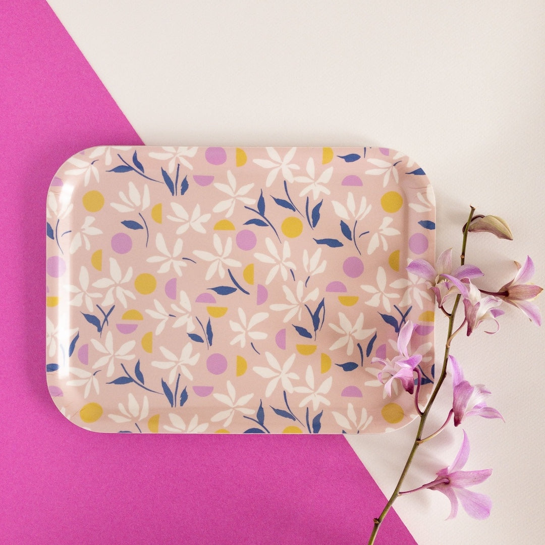 Floral-patterned tray on a pink and white background with a branch of flowers.