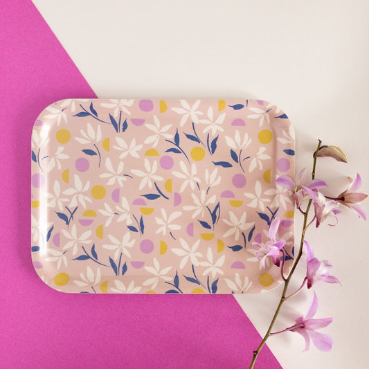 Floral-patterned tray on a pink and white background with a branch of flowers.
