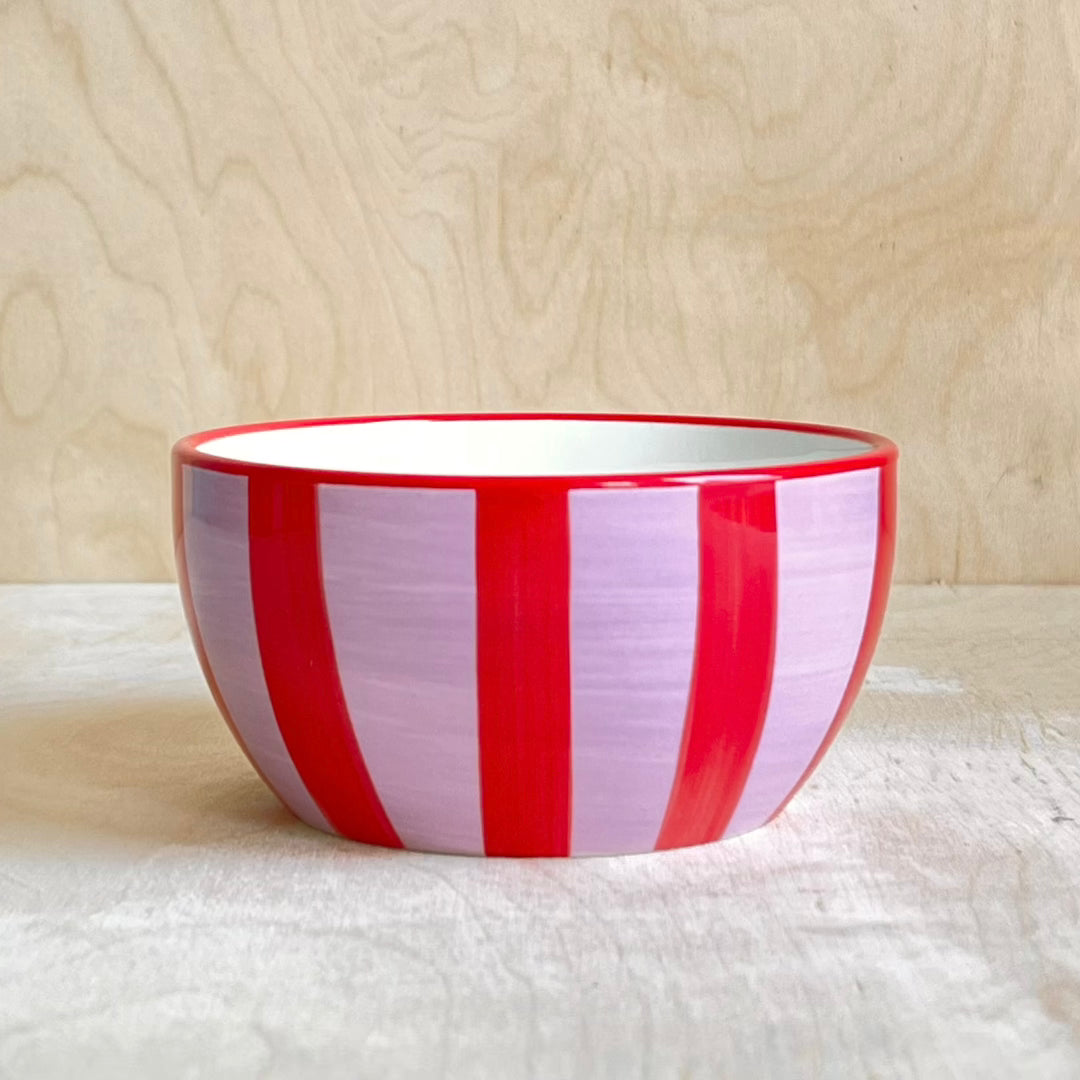 Red and pink striped bowl on a light wooden surface