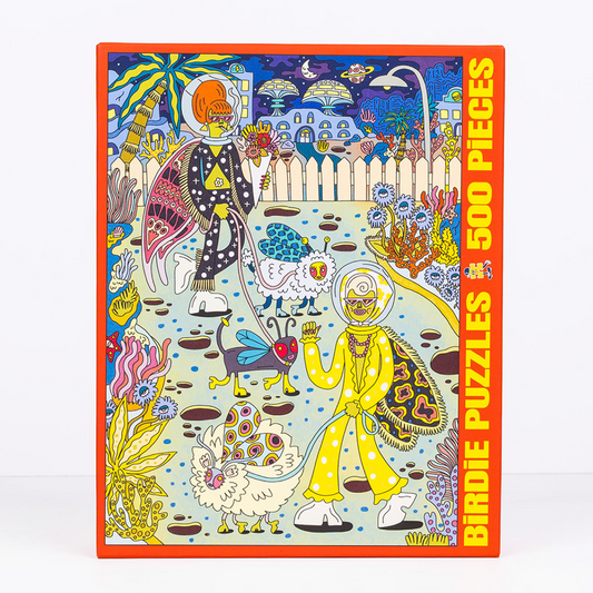 A 500-piece jigsaw puzzle box featuring a highly detailed, colorful psychedelic illustration of two figures in space suits walking in a surreal landscape. The box has a bright orange border and bold yellow text on the right side that reads 'BIRDIE PUZZLES 500 PIECES'.