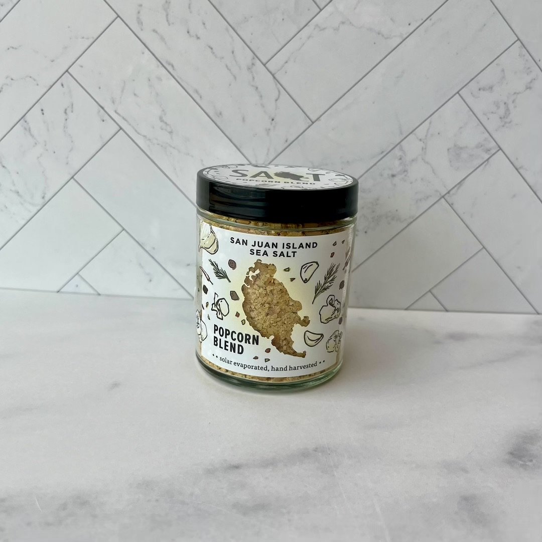 Jar of San Juan Island Sea Salt Popcorn Blend on a marble surface with a white tiled wall background