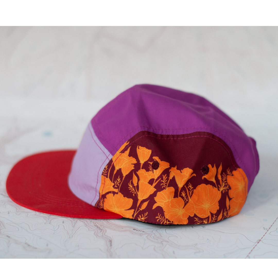 Colorful cap with purple top and red side with poppy floral pattern on a white background