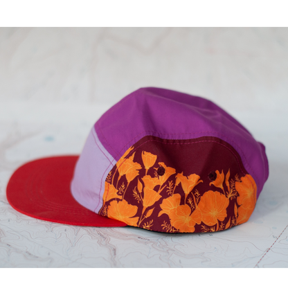Colorful cap with purple top and red side with poppy floral pattern on a white background
